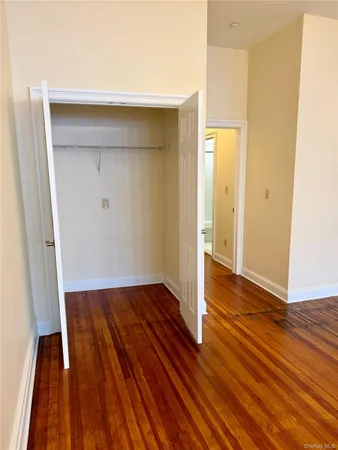 a view of an empty room with wooden floor and a ceiling fan