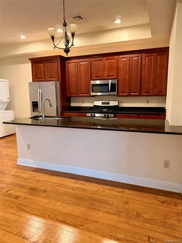 a view of kitchen with stainless steel appliances granite countertop a stove a sink and a microwave