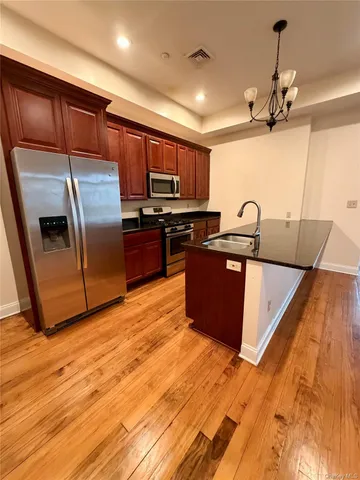 a kitchen with stainless steel appliances granite countertop a sink a stove top oven a counter space and cabinets