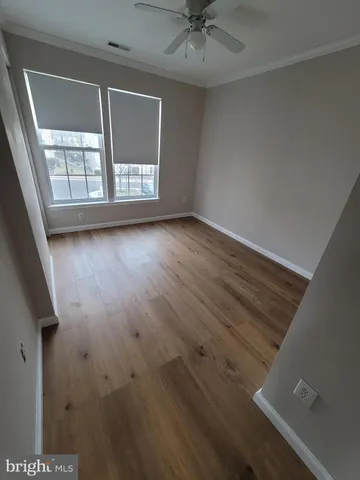 an empty room with wooden floor fan and windows
