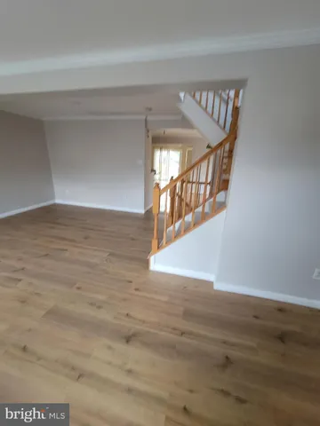 a view of an empty room with wooden floor and stairs