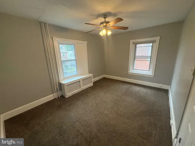 an empty room with windows and chandelier fan