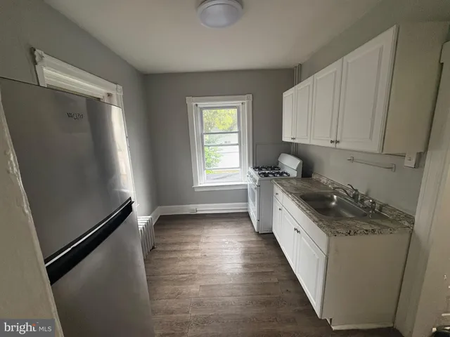 a kitchen with granite countertop a refrigerator a sink a stove and white cabinets
