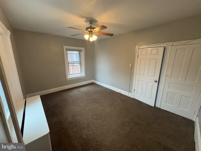 an empty room with windows and fan