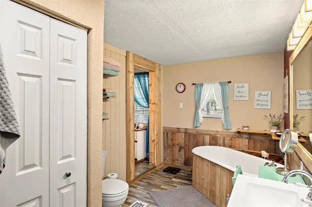 a bathroom with a granite countertop tub sink a mirror a toilet and shower