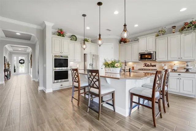 a kitchen with stainless steel appliances a dining table chairs microwave and sink