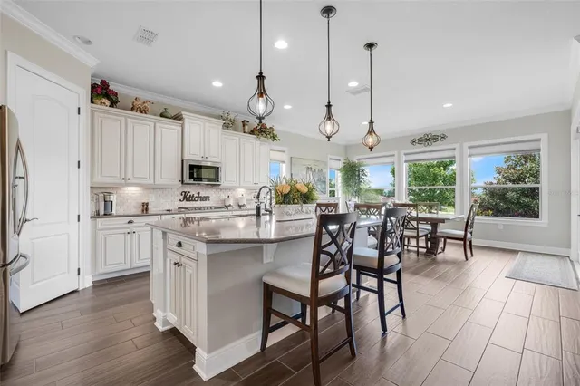 a kitchen with kitchen island granite countertop a table chairs sink and cabinets