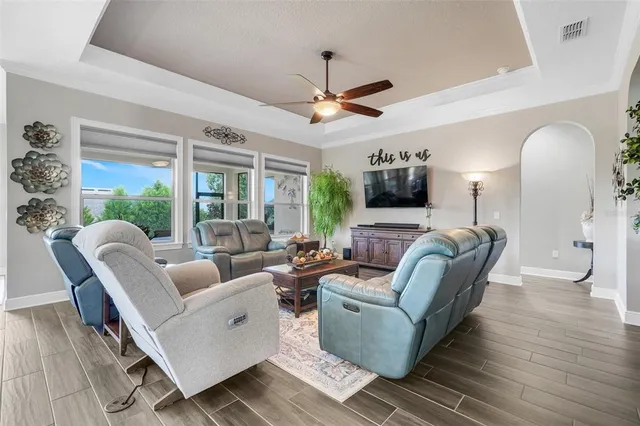 a living room with furniture a ceiling fan and a large window