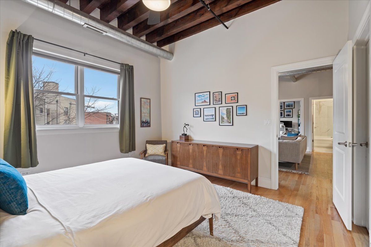 2310 West Nelson Street, Unit 302 Chicago, IL 60618 - Photo 13 of 20 a bedroom with a large bed a painting on the wall and a dresser