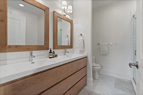 a bathroom with a double vanity sink toilet and mirror