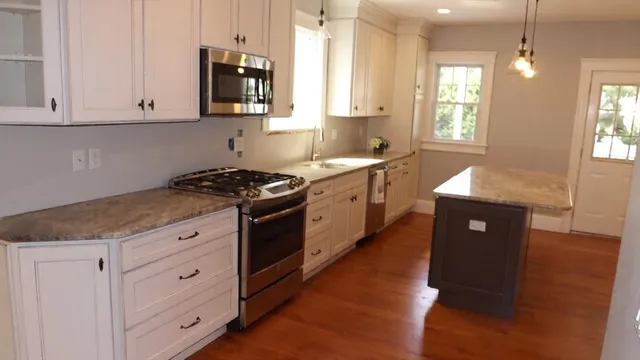 a kitchen with granite countertop white cabinets and window