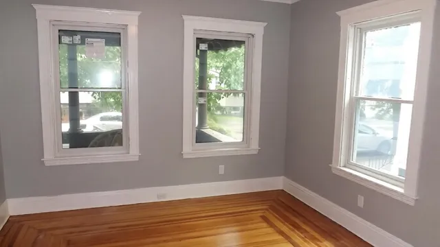 a view of an empty room with wooden floor and a window