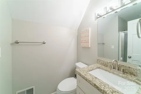 a bathroom with a granite countertop toilet sink and mirror