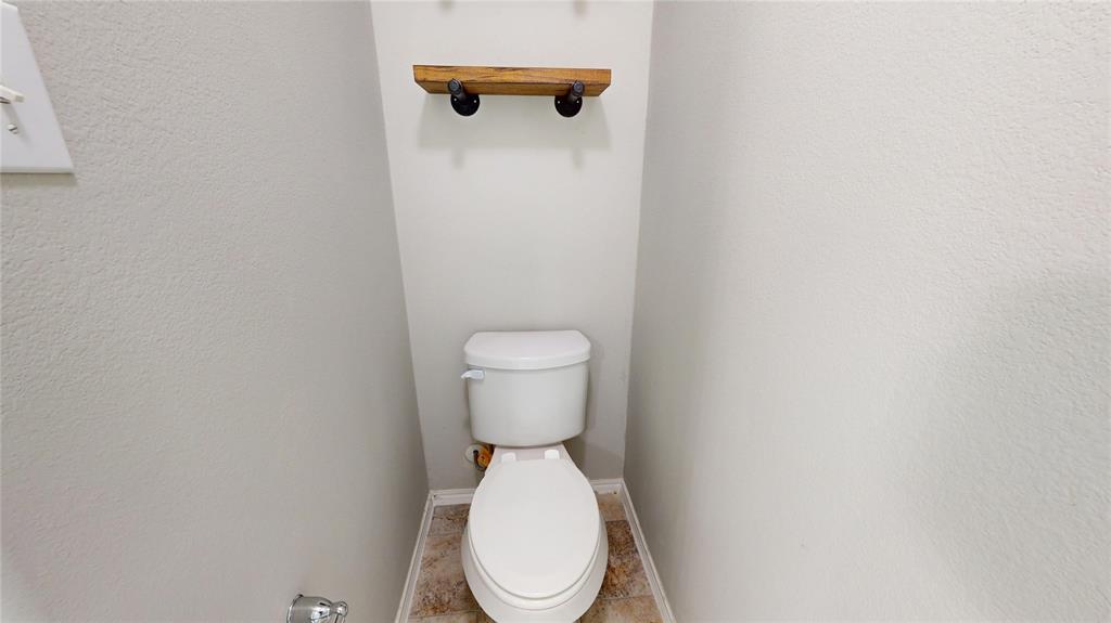3101 Buckthorn Street Forney, TX 75126 - Photo 19 of 40 White toilet with a built-in wooden shelf featuring metal brackets, set against light-colored walls and wood-finish flooring