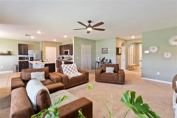 a living room with furniture kitchen view and a chandelier