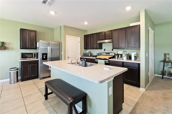 a kitchen with a refrigerator a microwave a sink and chairs