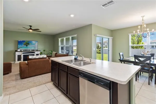a kitchen with a stove a sink a counter top space and living room view