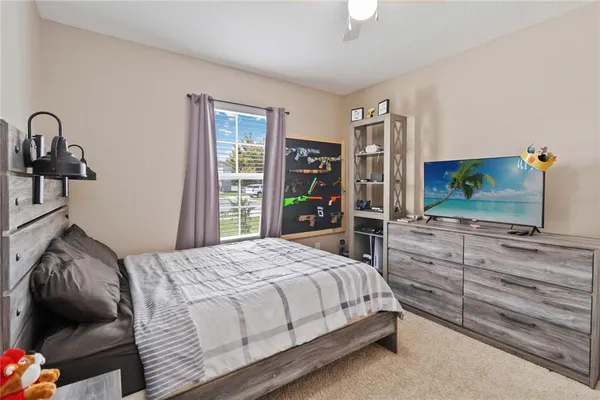 a bedroom with a bed and a flat tv screen on dresser