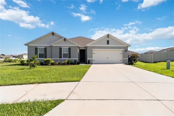 a front view of a house with a garden and trees