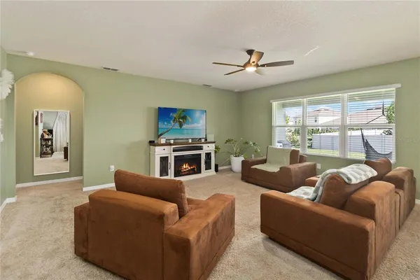 a living room with furniture a ceiling fan a fireplace and a large window