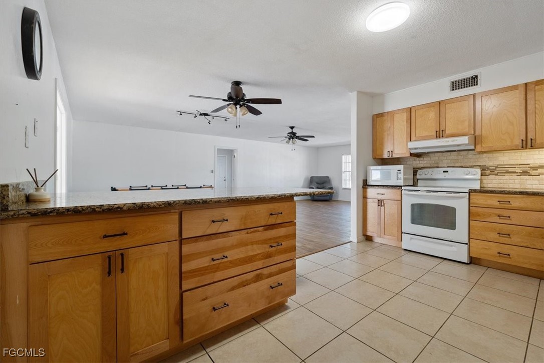 610 East Avenida Del Rio Clewiston, FL 33440 - Photo 14 of 49 a kitchen with granite countertop a stove a sink and a refrigerator