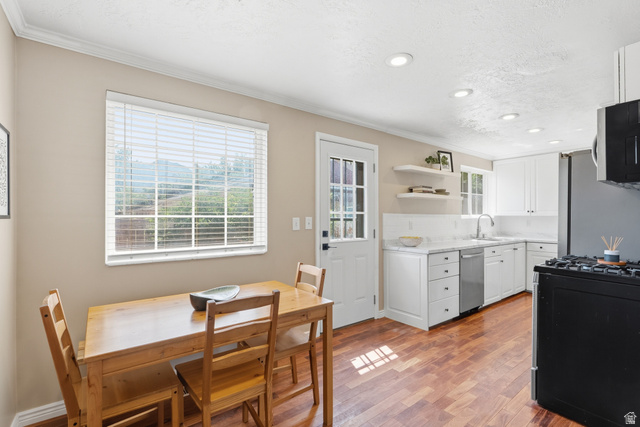 7795 South 1000 East Midvale, UT 84047 - Photo 13 of 42 Kitchen featuring wood-finish flooring, white cabinetry, integrated stainless steel dishwasher, white countertop, and recessed lighting