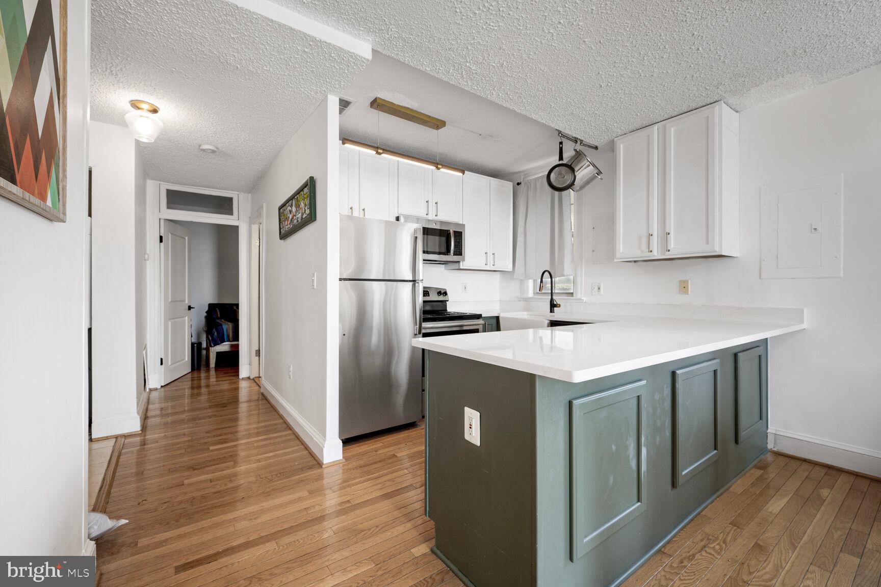 1401 Columbia Road Northwest, Unit 213 Washington, DC 20009 - Photo 3 of 14 a kitchen with kitchen island a sink stove and refrigerator