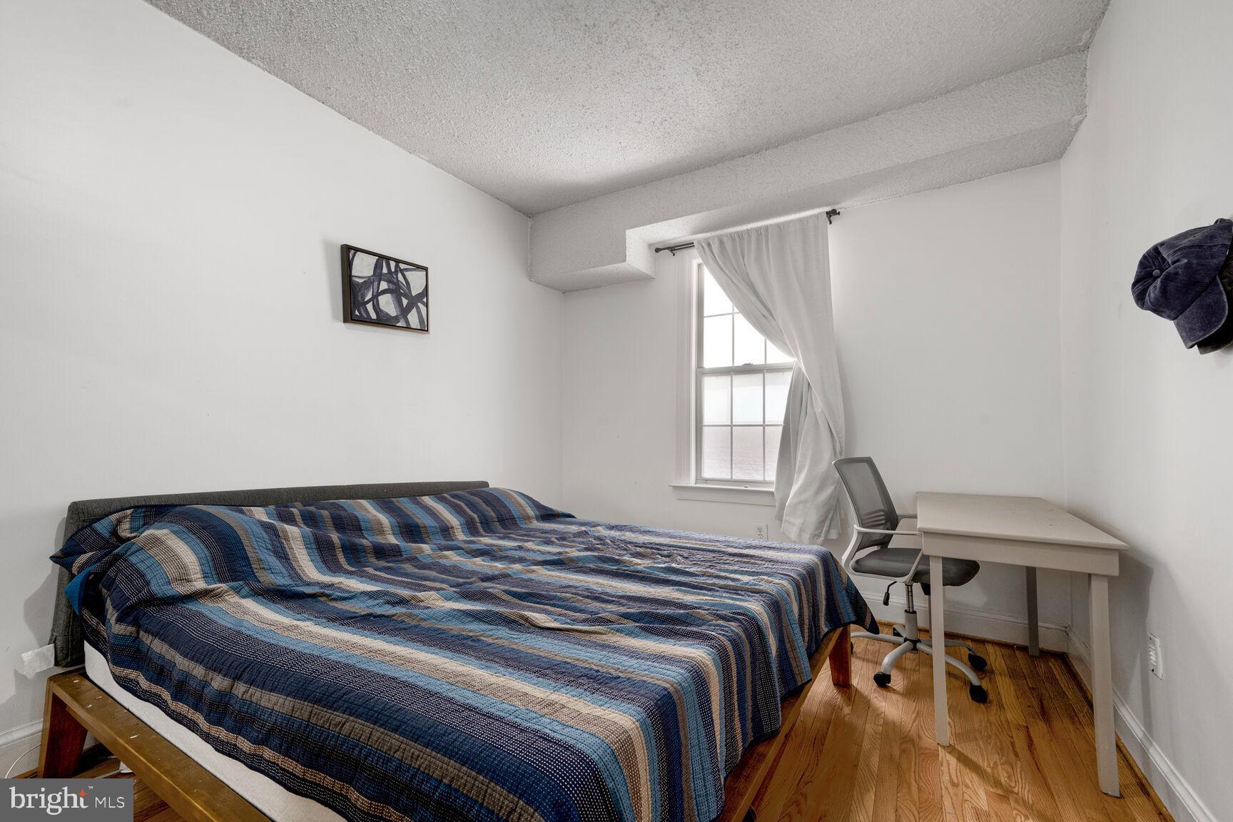 1401 Columbia Road Northwest, Unit 213 Washington, DC 20009 - Photo 10 of 14 a bedroom with a bed and wooden floor