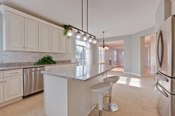 a kitchen with stainless steel appliances granite countertop a refrigerator a stove and white cabinets with wooden floor