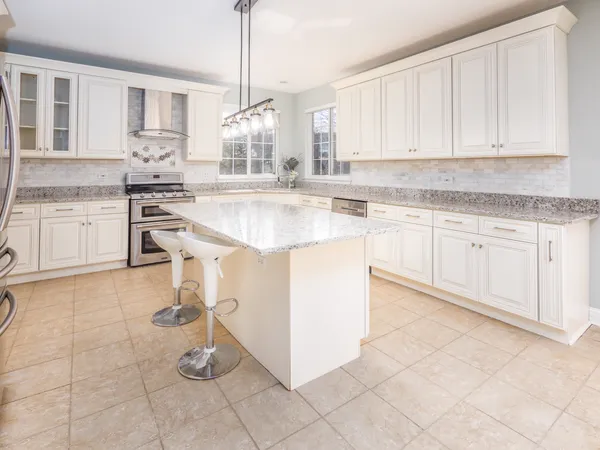 a kitchen with stainless steel appliances granite countertop a stove a sink and white cabinets