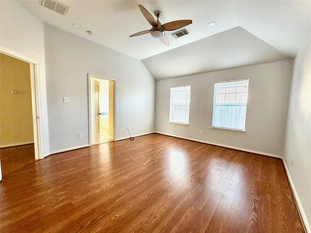 an empty room with wooden floor fireplace and windows