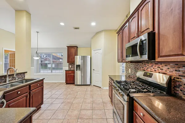 a kitchen with stainless steel appliances granite countertop a stove a sink and a microwave
