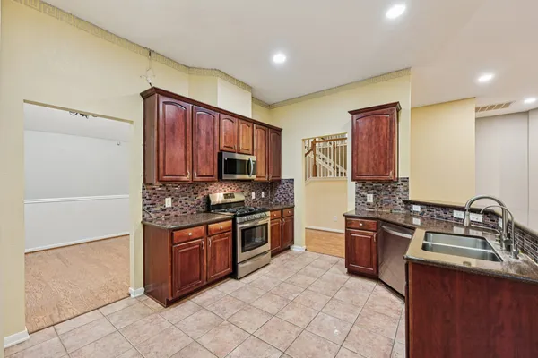 a kitchen with stainless steel appliances granite countertop a stove top oven sink and cabinets