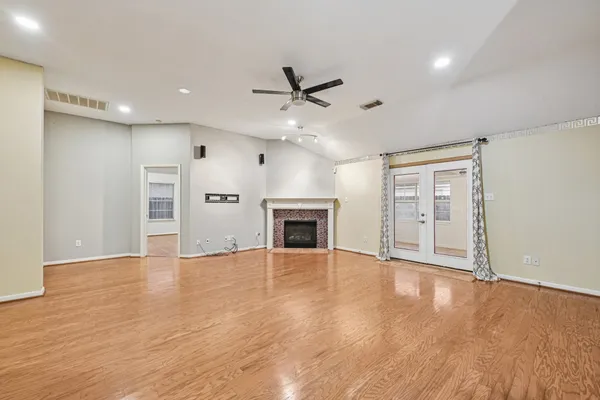 an empty room with wooden floor fireplace and windows