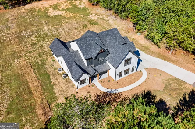 an aerial view of a house with backyard and swimming pool