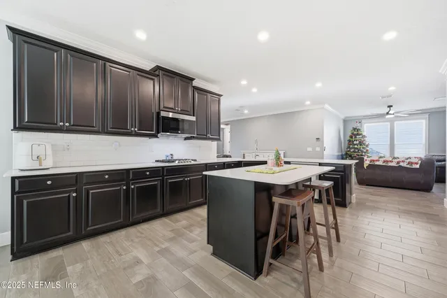 a kitchen with stainless steel appliances granite countertop a sink dishwasher a stove a refrigerator with a dining table and chairs