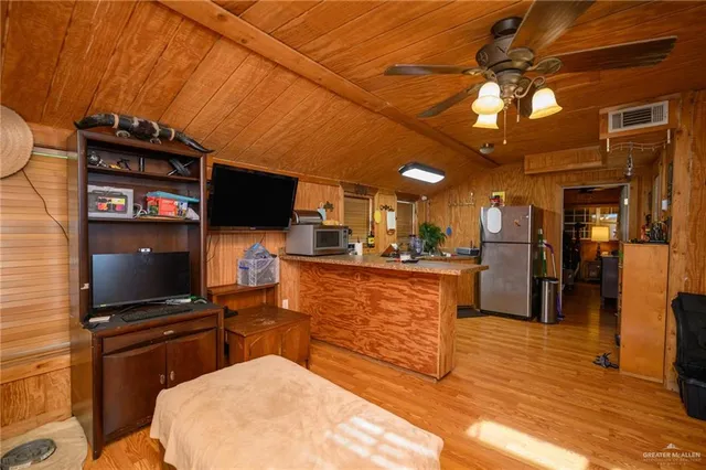 a living room with stainless steel appliances furniture a flat screen tv and kitchen view