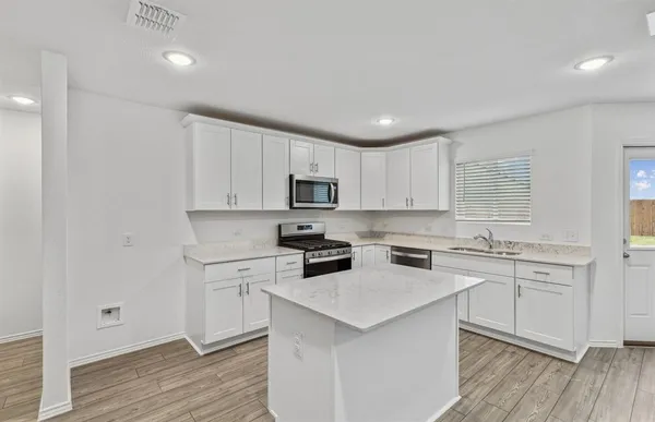 a kitchen with a sink a stove a refrigerator and white cabinets