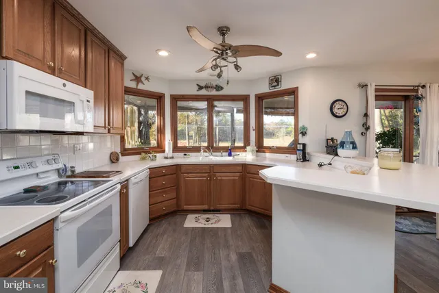 a kitchen with stainless steel appliances kitchen island granite countertop a table chairs and a refrigerator