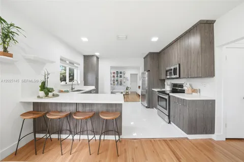 a large kitchen with kitchen island granite countertop a wooden floor and cabinets
