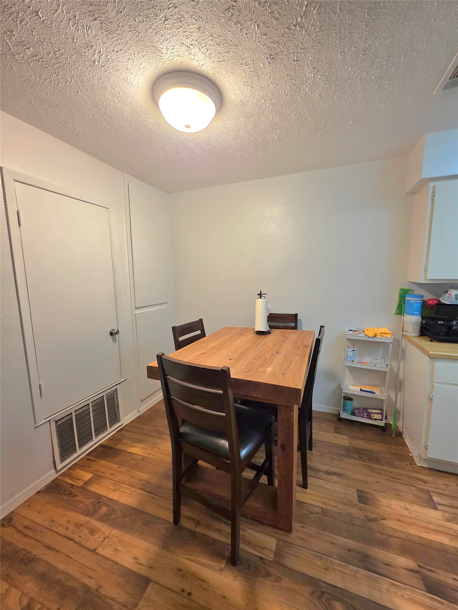 15208 Spring Hill Lane, Unit A Pflugerville, TX 78660 - Photo 10 of 16 Wood-finish flooring provides a warm aesthetic to this dining area, complemented by a surface-mounted ceiling light fixture