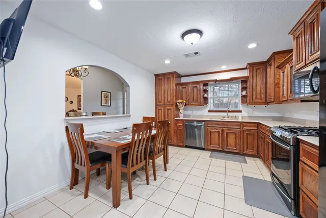 a kitchen with stainless steel appliances kitchen island granite countertop a stove a sink a dining table and chairs