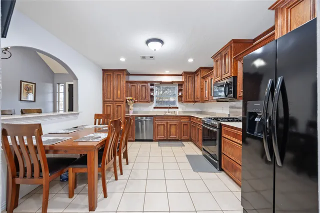 a kitchen with stainless steel appliances granite countertop a stove top oven a sink a dining table and chairs
