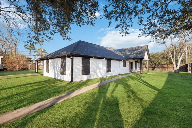 a view of a house with a big yard potted plants and large tree