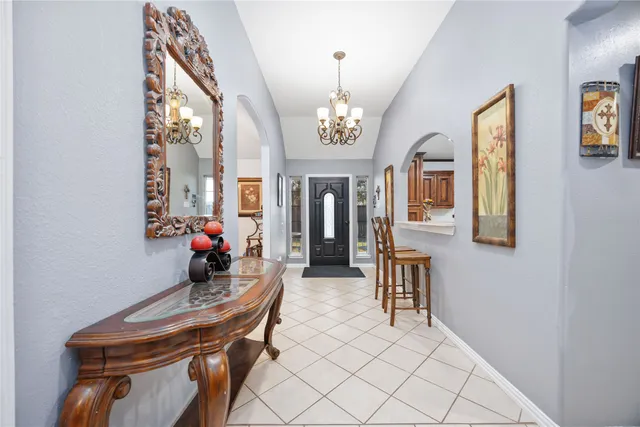 a view of a hallway to a livingroom with furniture wooden floor chandelier and windows
