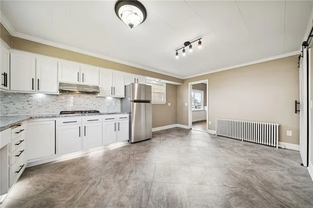 a large white kitchen with a window and refrigerator