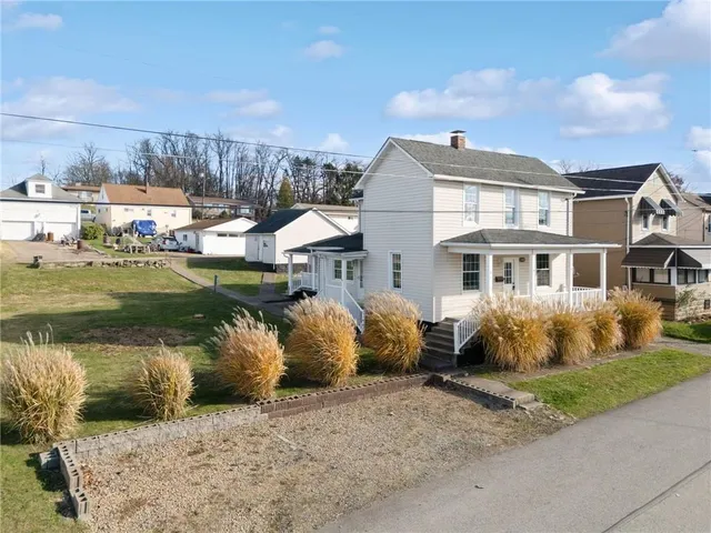 a front view of a house with a garden and lake view