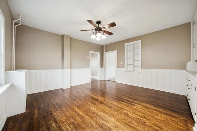 a view of an empty room with window and wooden floor