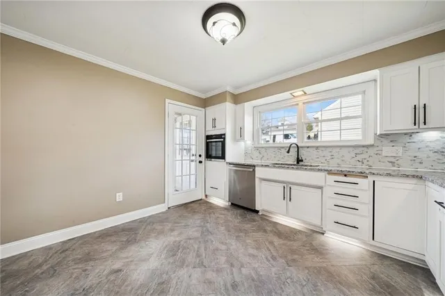 a large kitchen with granite countertop a stove a sink dishwasher and a refrigerator with wooden floor