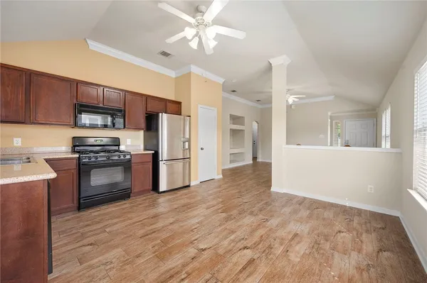 a kitchen with granite countertop a refrigerator and a stove top oven